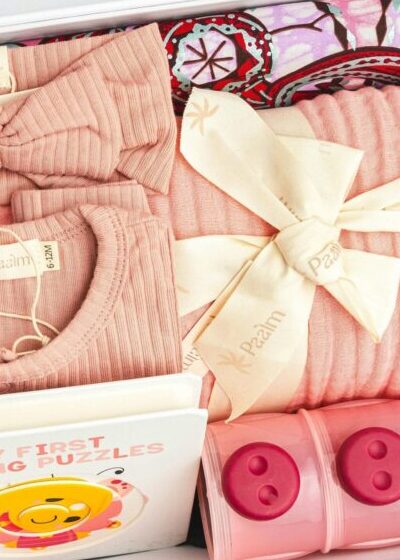 Adorable baby gift box featuring pink clothing, a puzzle book, and storage containers.